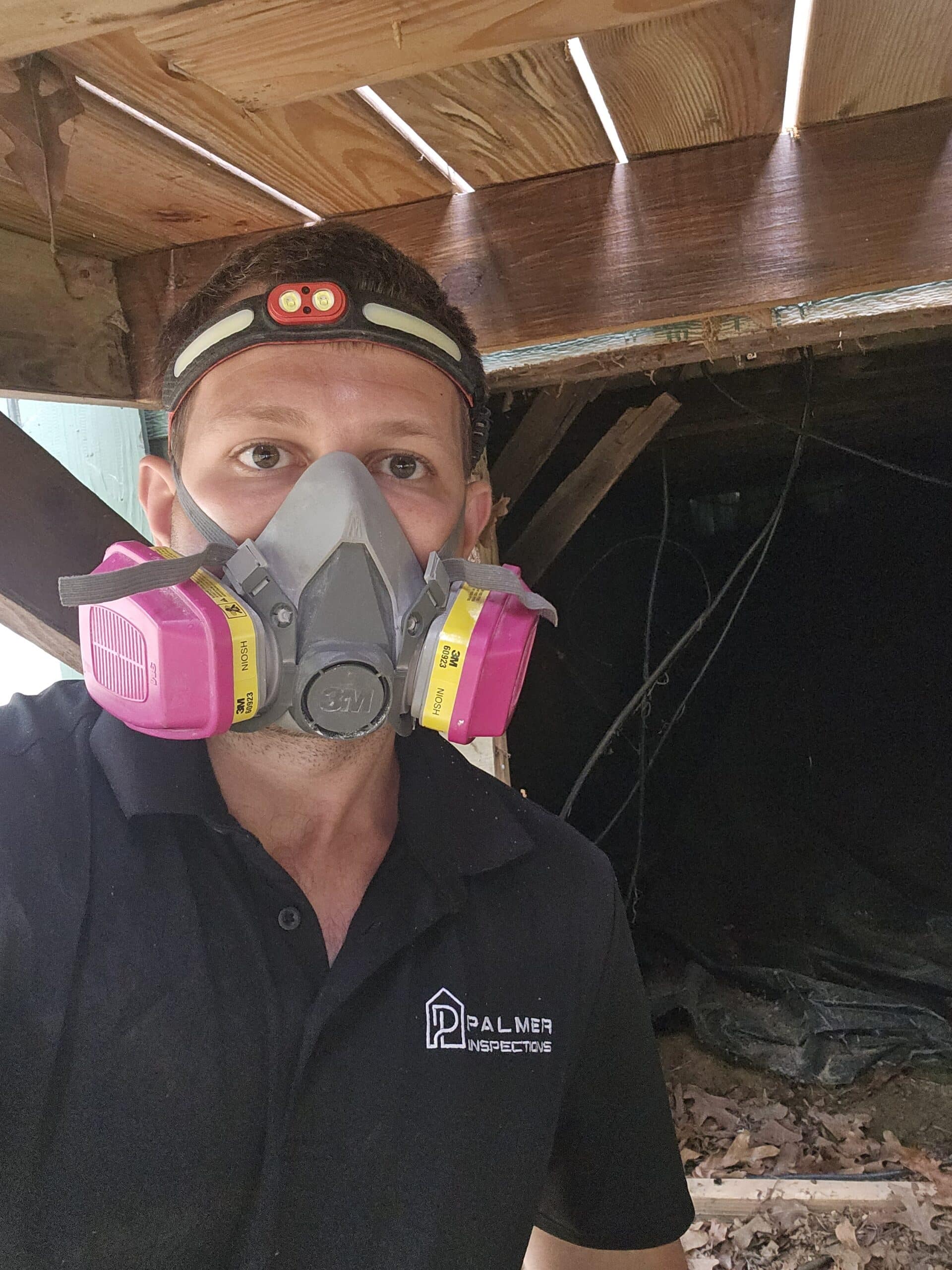 Inspector wearing protective respirator and headlamp while examining a crawl space during a WDI termite inspection in East Texas.