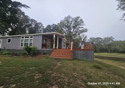 Manufactured home with attached porch and deck addition on a sloped lot, used to illustrate foundation and addition certification inspections in East Texas.