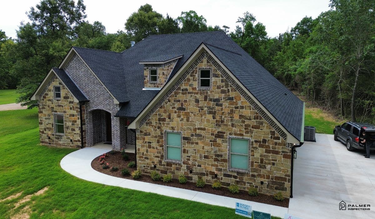 residential-exterior-home-inspection-east-texas Drone view of a brick and stone home in East Texas highlighting the 2027 Housing Outlook for East Texas and the growing importance of professional home inspections for buyers and homeowners.